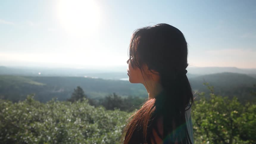 A woman brushes her hair back on the mountain