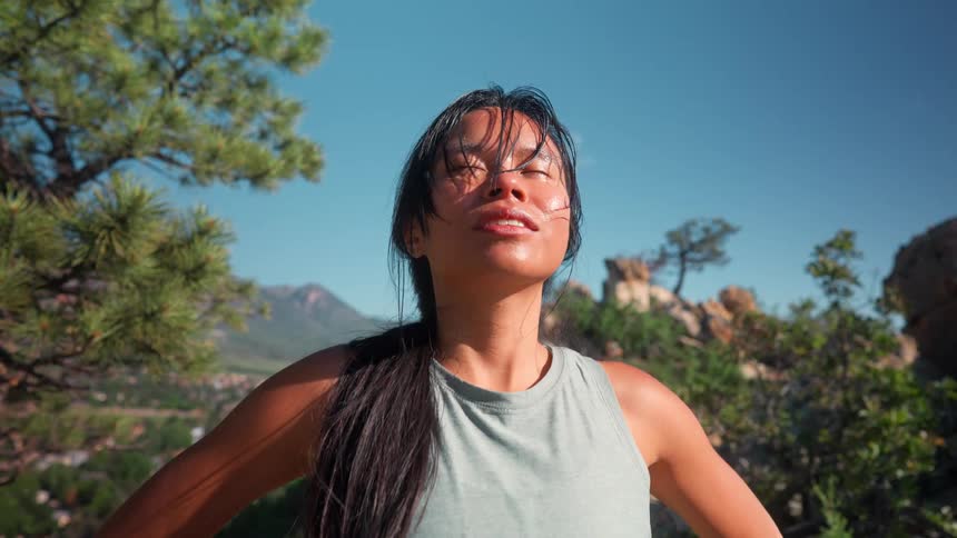 A female standing outside breathing heavy and sweating under the sun