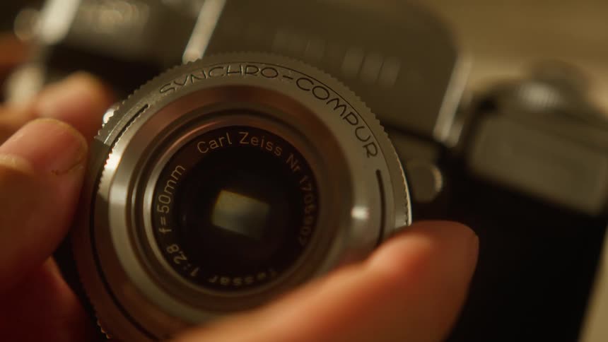 Close up of a person adjusting a cameras lens on a table