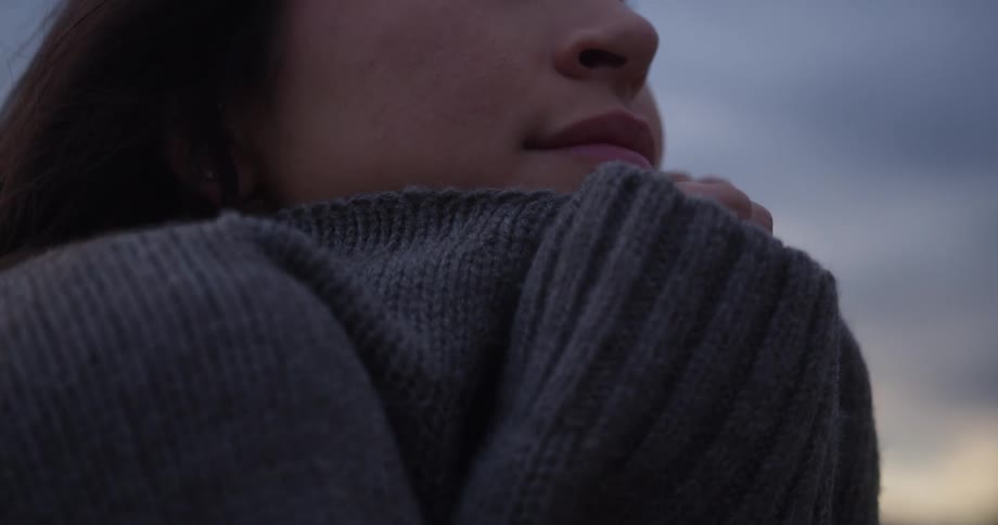 A woman holds her arms tight to her chest
