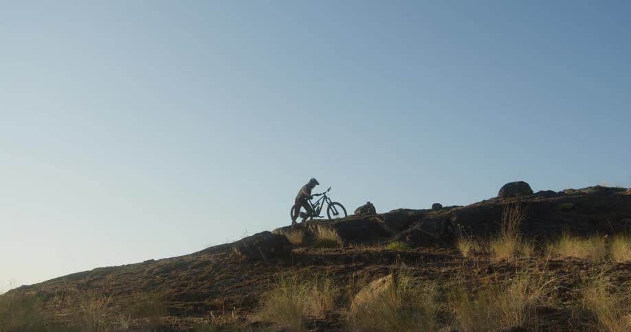 The man is pushing his bike up the mountain