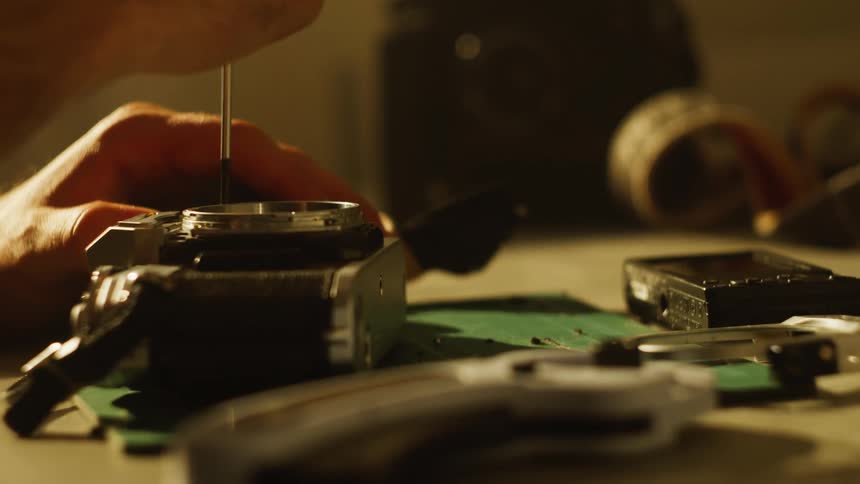 Person with a tool unscrewing a vintage camera