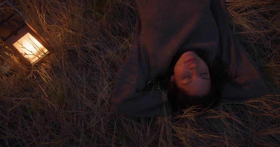 A woman is sleeping outdoors in the grass at night