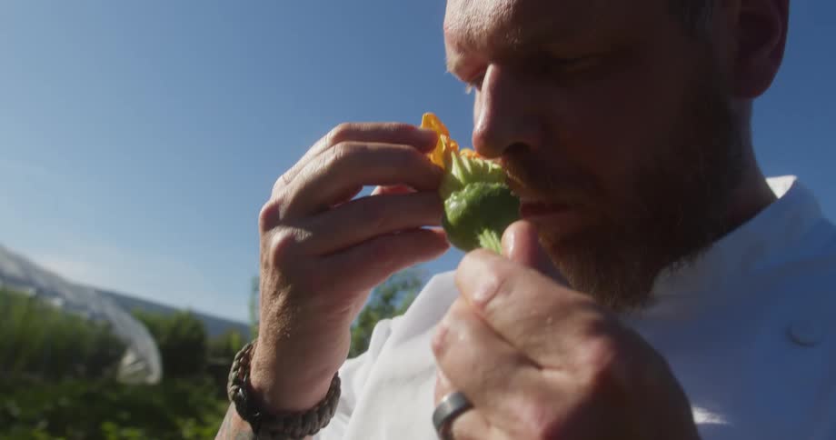 Man smelling fresh produce outdoors under clear sky