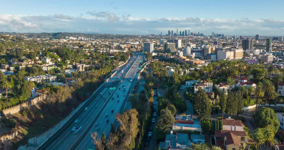 A wide aerial view of a major highway running through a sprawling urban  Los Angeles  cityscape