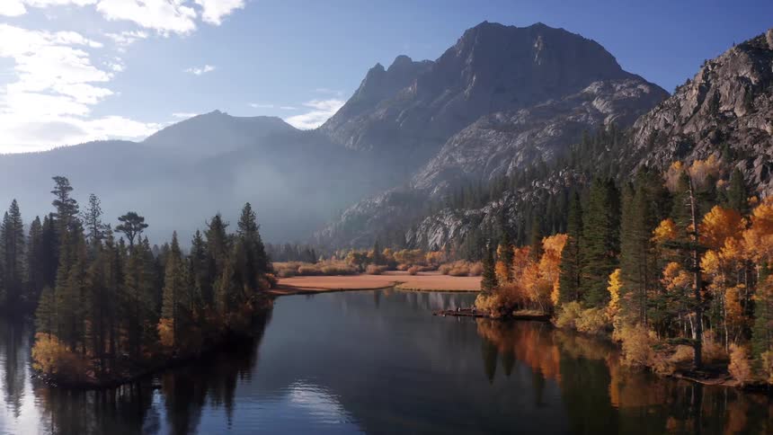 Silver Lake, California borders an autumn forest beneath a towering mountain in clear daylight