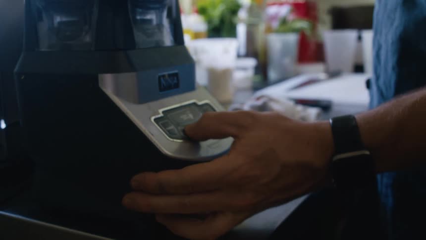 The cook presses the button on the blender