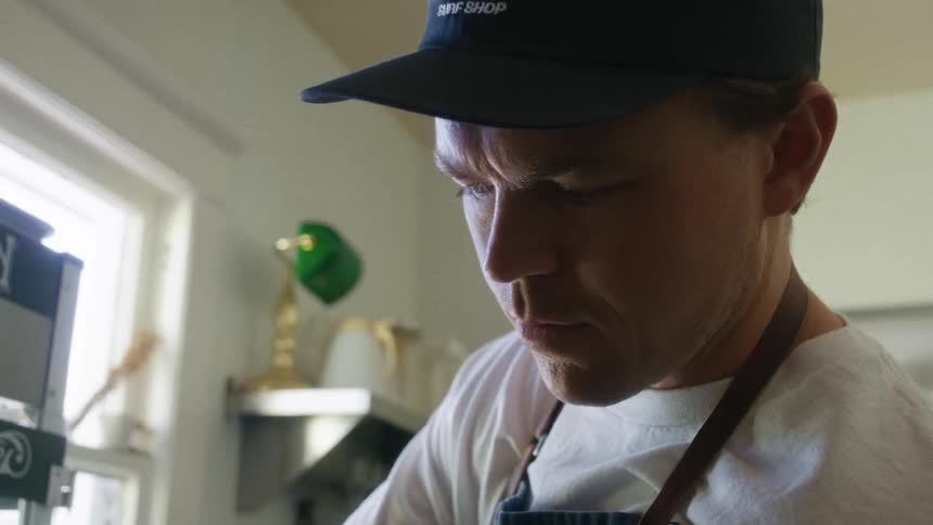 Man in cap with apron in a concentrated indoor space