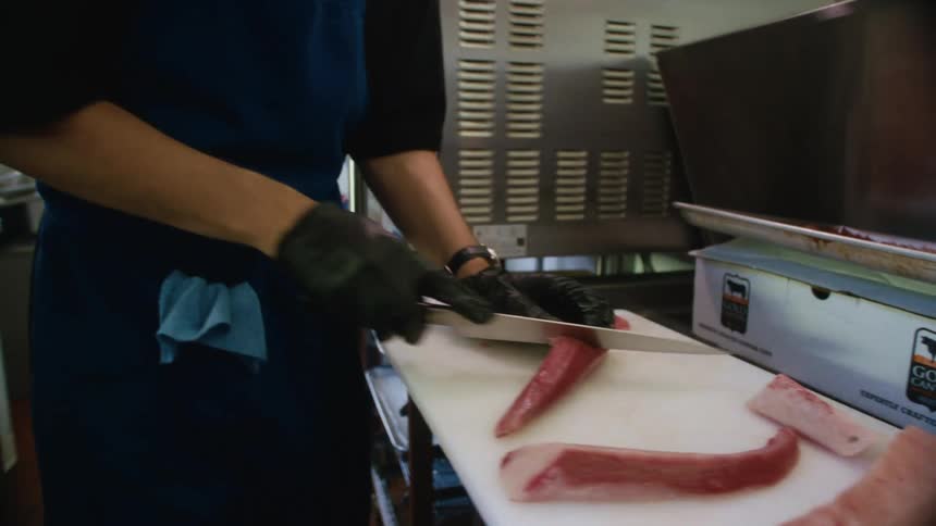 Chef with gloves and a knife cutting a meat
