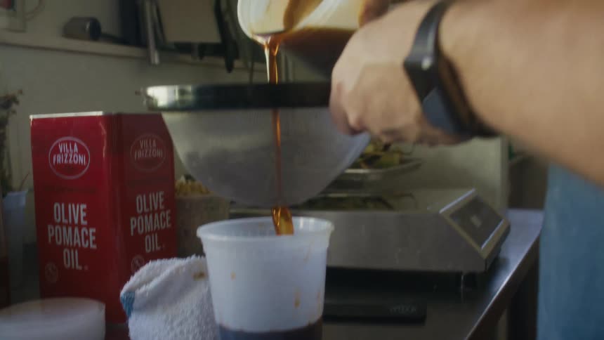 Dark sauce being strained through a sieve