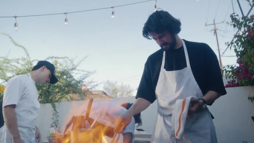 Three men in aprons cooking outdoors