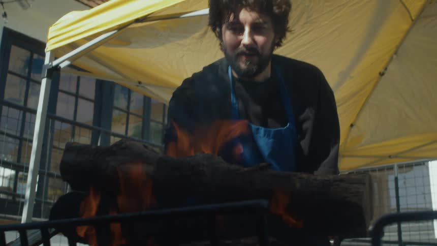 A man is burning logs by the tent