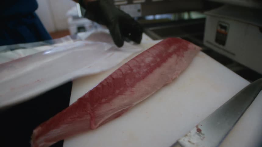Close up of a chef unpacking meat from a bag on a chopping board in the kitchen