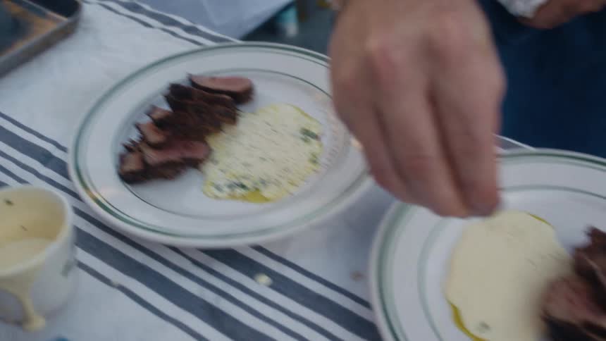 A cook is sprinkling spices on the dishes