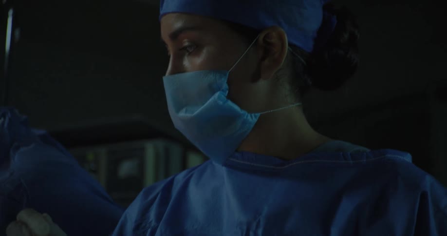 Doctors use surgical scissors to operate on a patient in the theater while an assistant hands them tools
