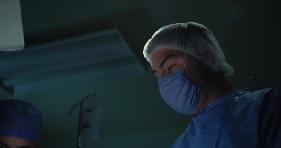 A surgeon is handed a tool while performing surgery