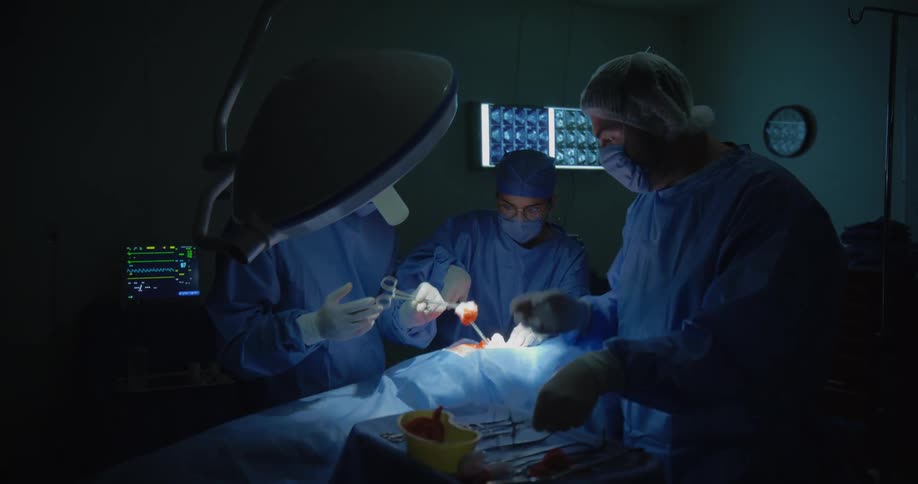 Three focused doctors performing surgery on a patient