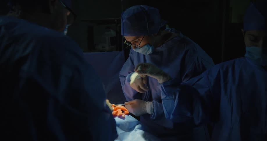 Two surgeons and an assistant perform a surgery in an operating theatre