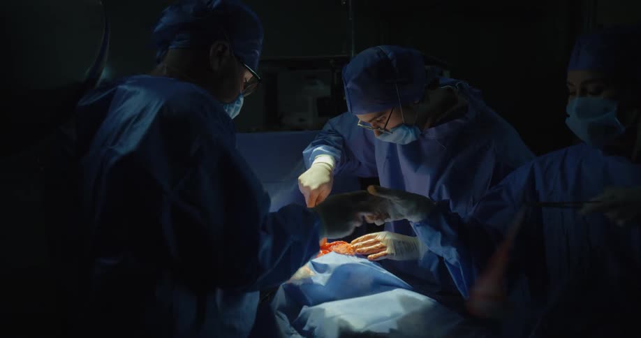 Group of surgeons perform a surgery on patient in an operating theatre