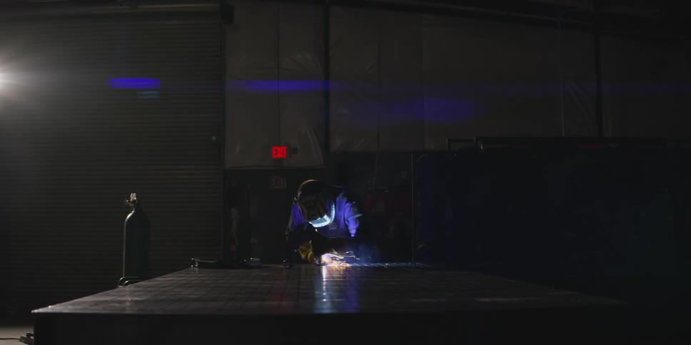 Person with a protective helmet welding a metal and emitting sparks