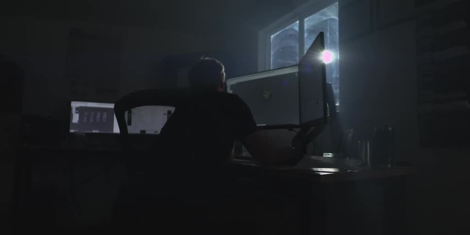 Man sitting working in a dark room in front of a computer