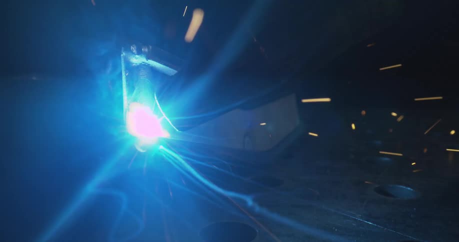 Bright sparks fly as metal is welded under a vivid blue light