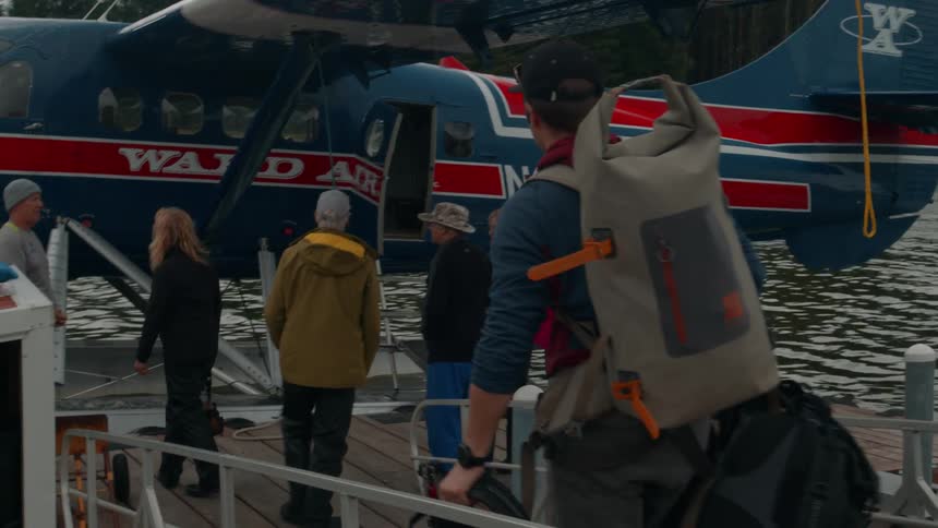 Luggage is carried toward the plane in the water where people are waiting to get on