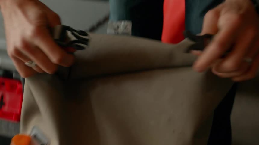 Pair of hands closing a backpack