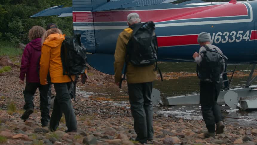 Group of travelers with backpacks walking towards the plane