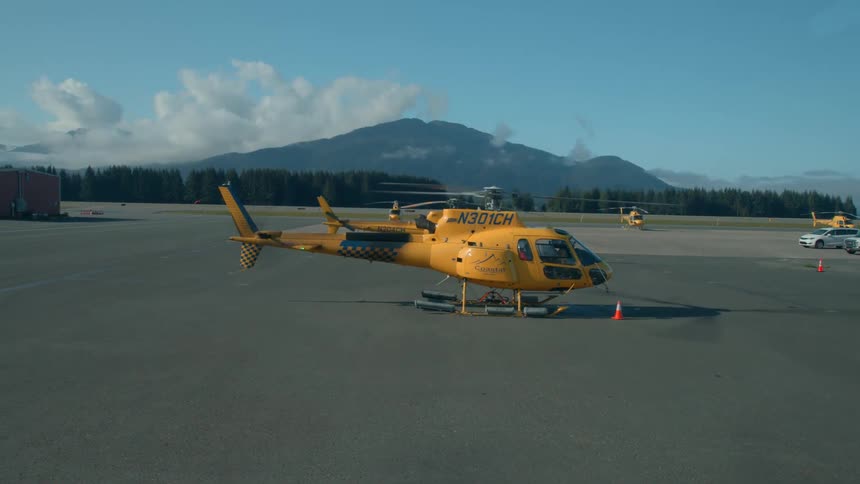 Helicopter on a flat area with the propeller moving and mountains in the background
