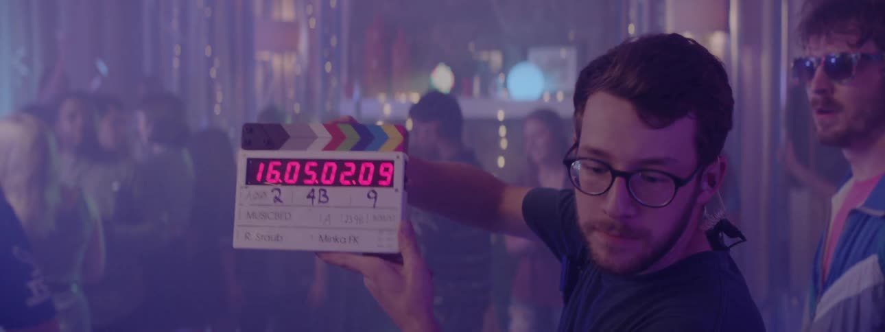 A man closes a movie clip board to start a scene