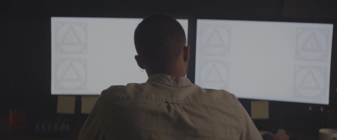 A man walking around and then sitting down at a desk
