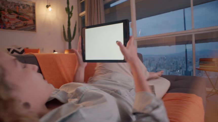Woman lying in living room interacting with a tablet