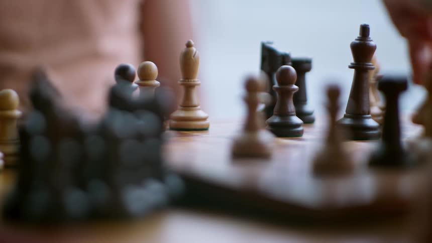 Closeup of a chessboard and two hands of different people judging a chess match