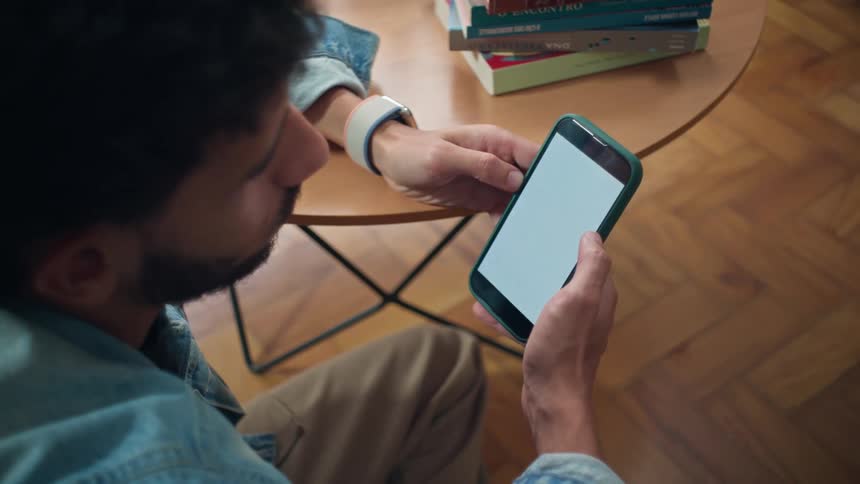 Male sitting at a round table looking at his phone