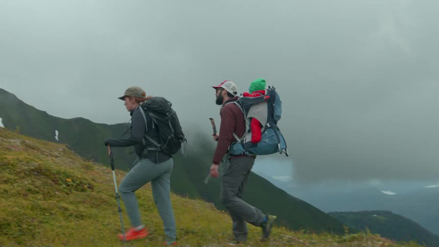 Group of people including a baby hiking in the mountains on a cloudy day