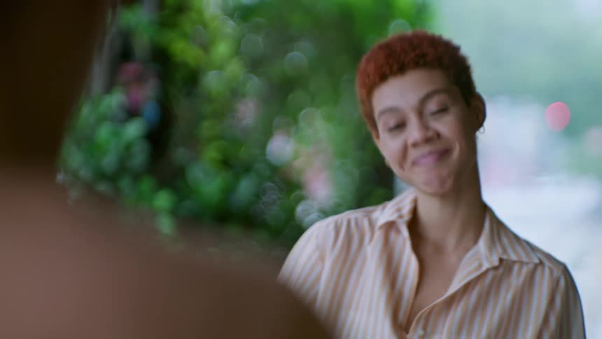 Curly haired woman sitting talking to another person