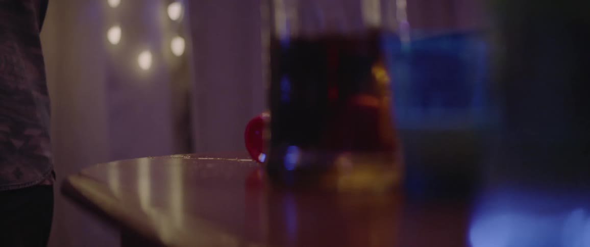 A close up of a table with lights flashing in the background and someone dropping a cup on the table