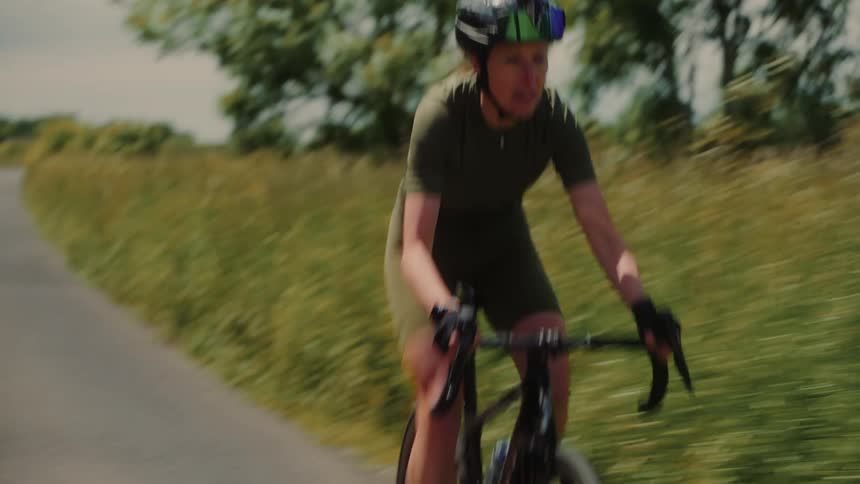 Woman bike riding fast through a rural landscape