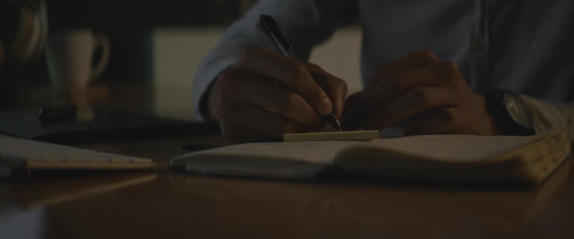 A man writes in a notebook
