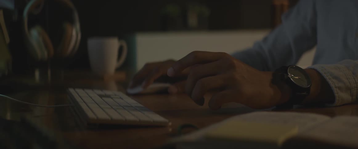 A man sits at a desk and uses a mouse and keyboard