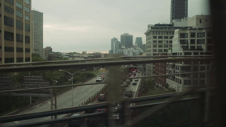 Multiple vehicles drive on a highway through a city