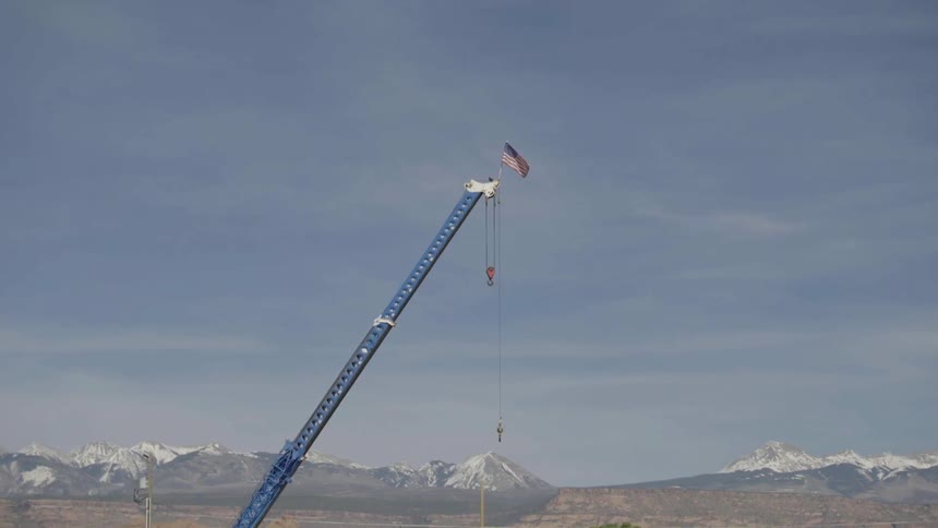 An american flag flies from the top of a crane