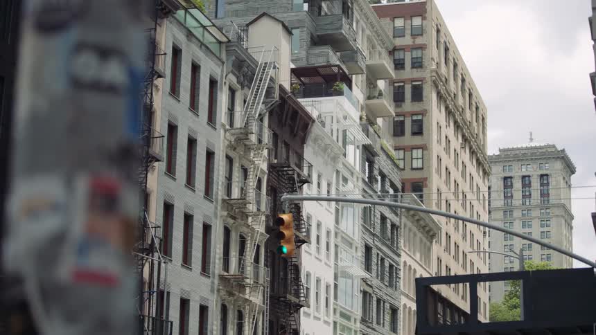 A streetlevel view of a bustling urban environment likely in a major city characterized by a mix of old and new architecture the sky appears overcastin the foreground on the far left theres a heavily stickered or posted pole