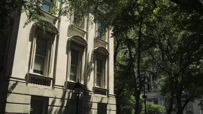 A twostory building with three windows on both the first and second floors is surrounded by trees at midday
