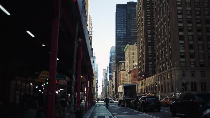 Street in a metropolis with tall buildings and busy with vehicle and pedestrian traffic