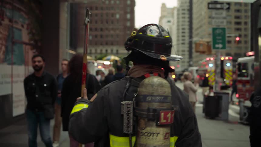 The firefighter walks to the corner in the city