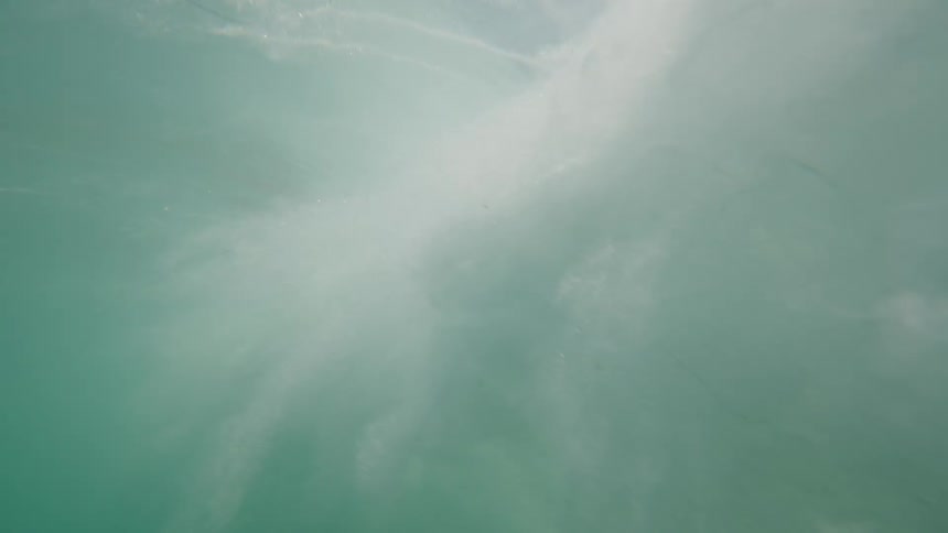 The wave crashes shooting foam underwater
