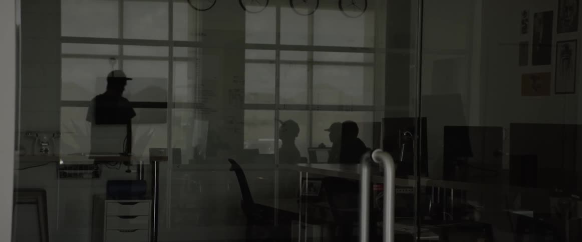 The silhouettes of several people with baseball caps shows through the windows