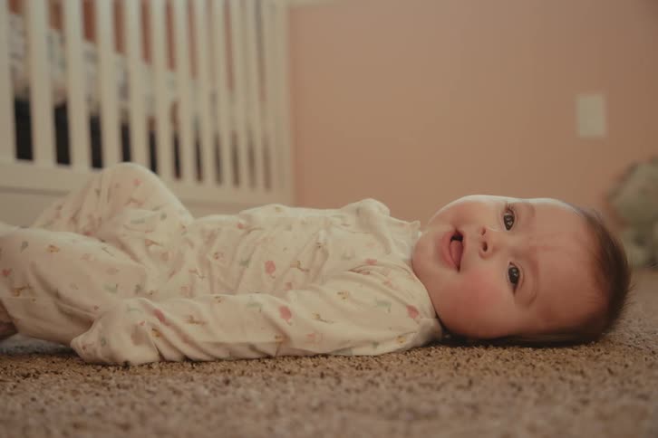 Baby lying on a rug in a room
